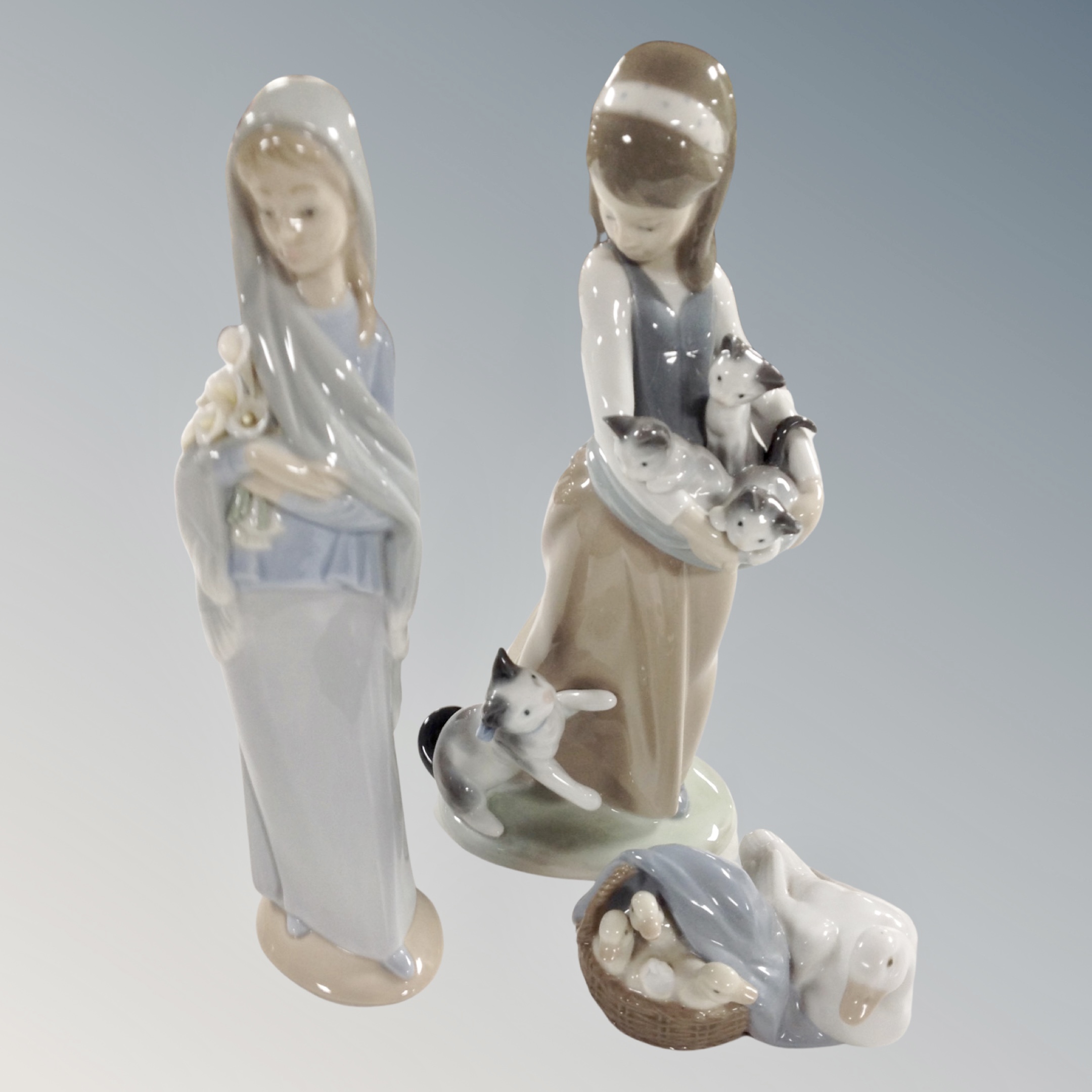 A Lladro lady with kittens together with a further Lladro figure of a lady carrying flowers and a