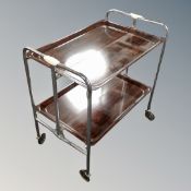 A 20th century metal and Bakelite two-tier folding serving trolley in a rosewood-effect finish.