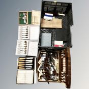 A crate containing canteens and boxes of assorted cutlery.