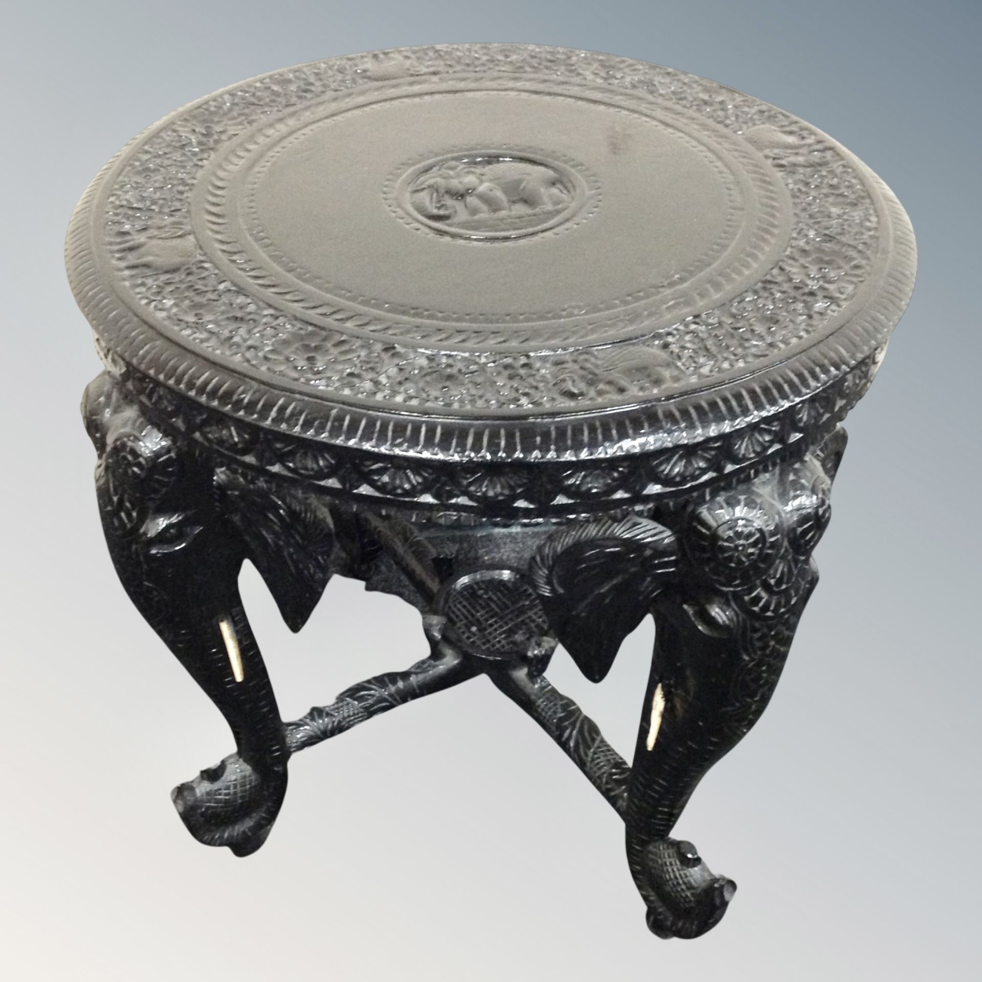 An ebonised Indian carved circular occasional table on elephant legs