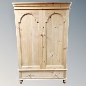 A pine double door wardrobe fitted with a drawer
