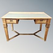 An early 20th century oak two drawer writing table with leather inset panel and understretcher