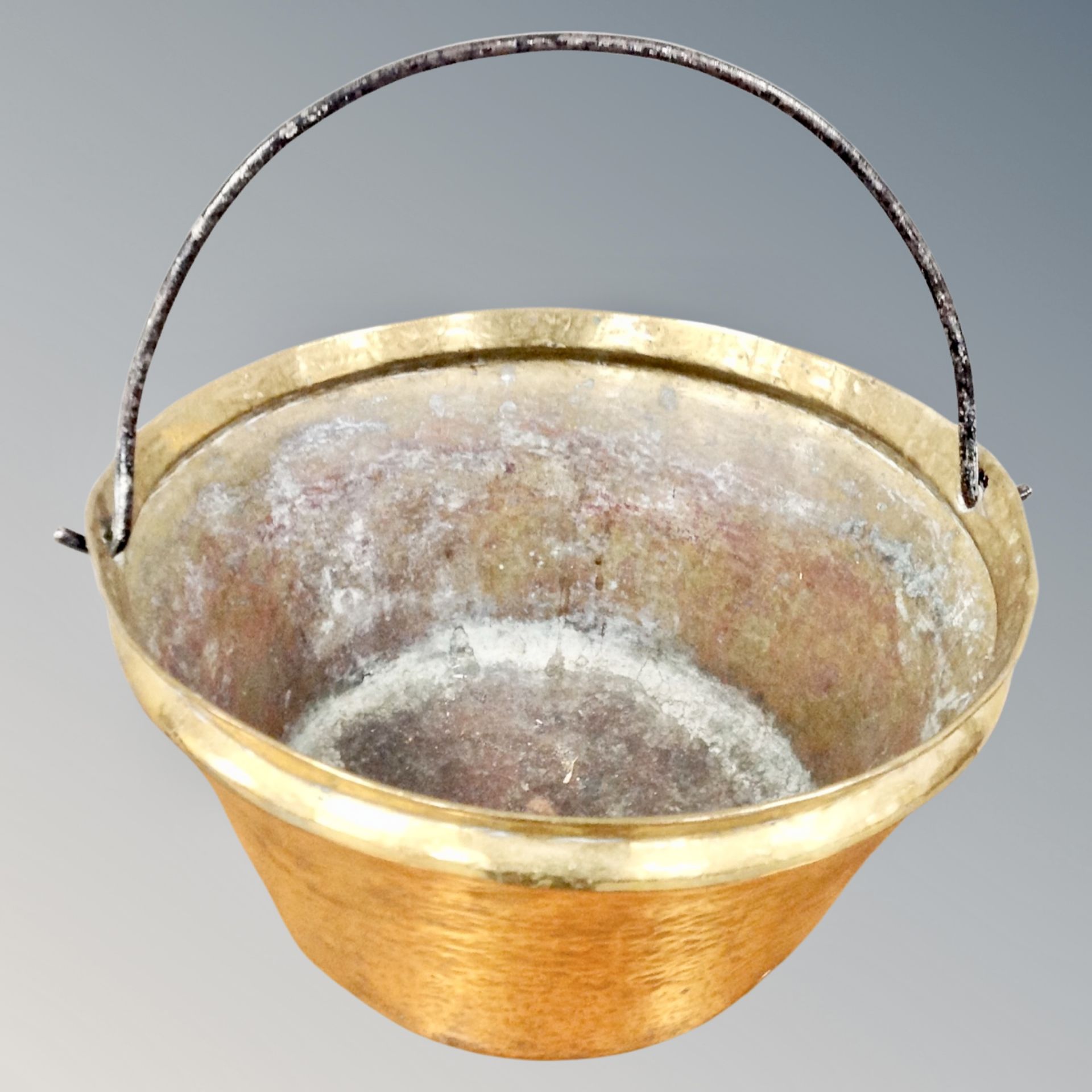 A 19th century hammered brass swing-handled cooking pot