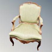 A French carved walnut open armchair in green fabric
