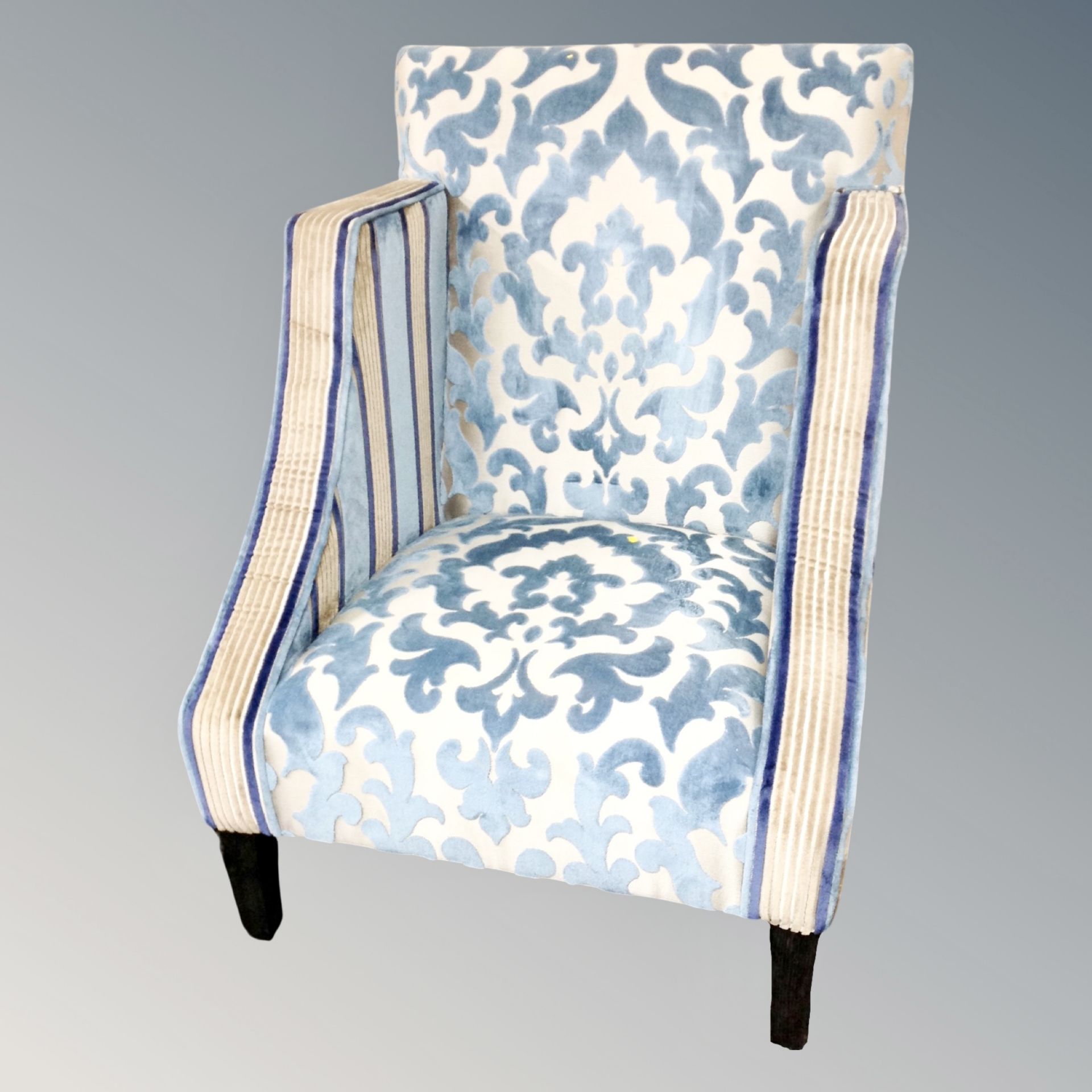 A contemporary high backed armchair in blue and golden fabric
