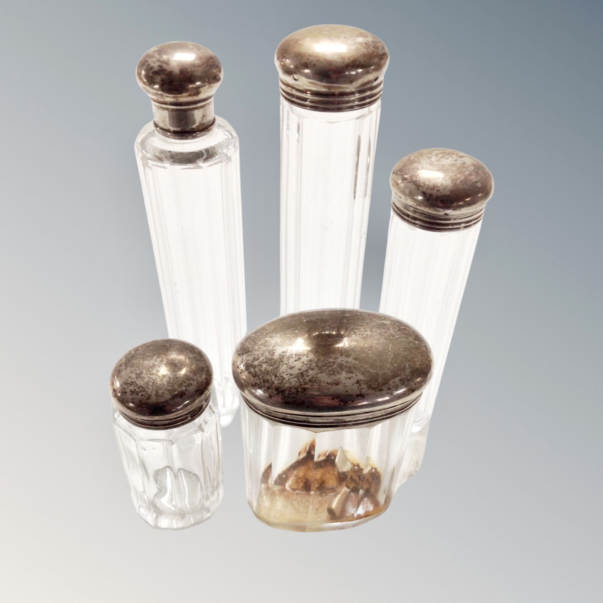 Five glass silver-topped dressing table jars.