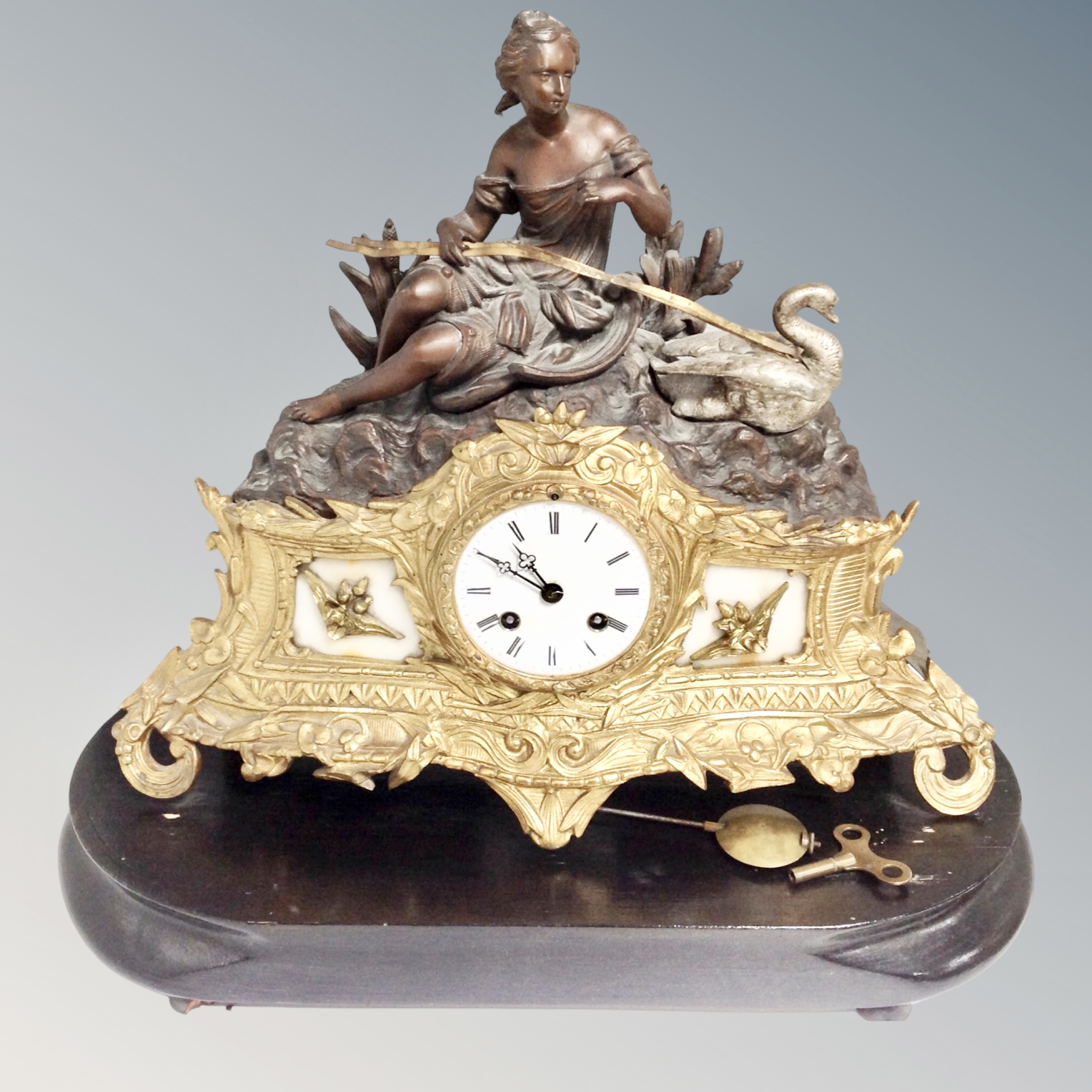 A 19th century gilt-brass and spelter mantel clock surmounted by female figure with swan on wooden