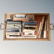 An Edwardian oak twin handled tray containing Art Deco desk stand, collection of letter openers,