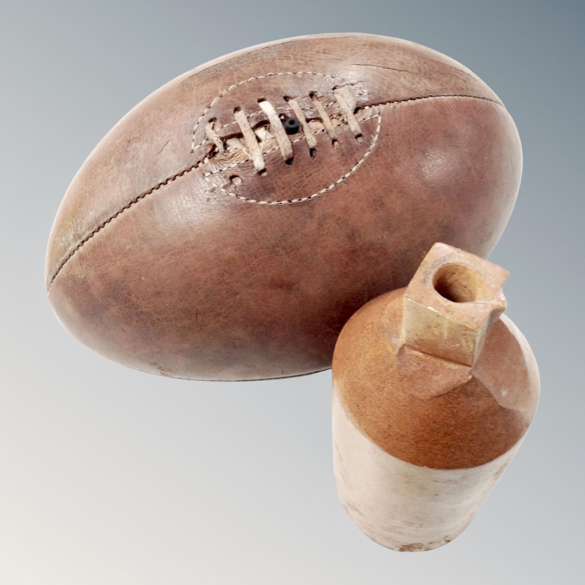 A vintage leather rugby ball and a stoneware bottle