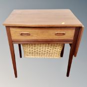 A 20th century teak flap sided work table fitted with drawer and basket