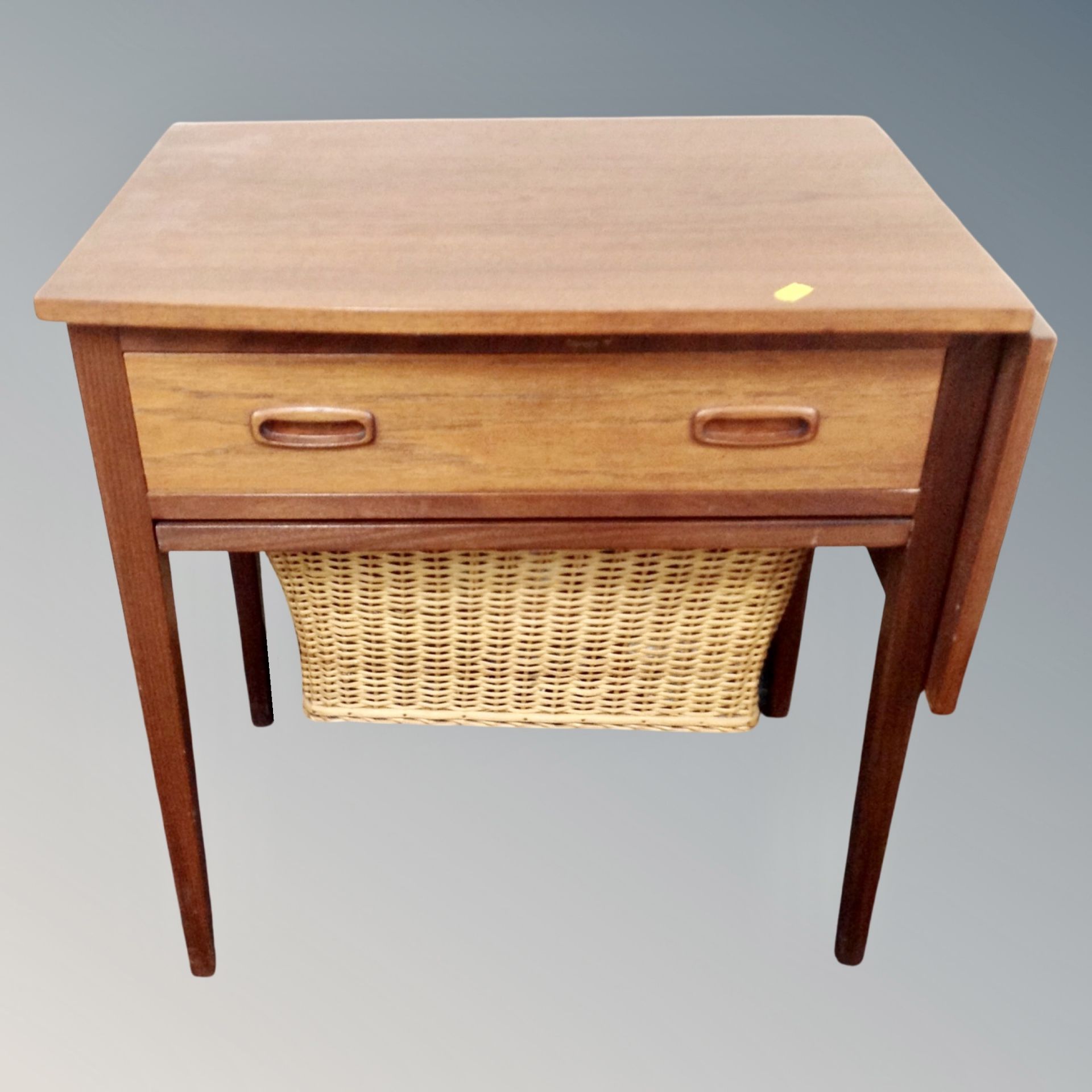 A 20th century teak flap sided work table fitted with drawer and basket