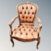 A carved beech framed armchair in brown buttoned leather