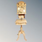 A Genfa blond oak wall clock with pendulum and key together with a further blond oak pedestal table