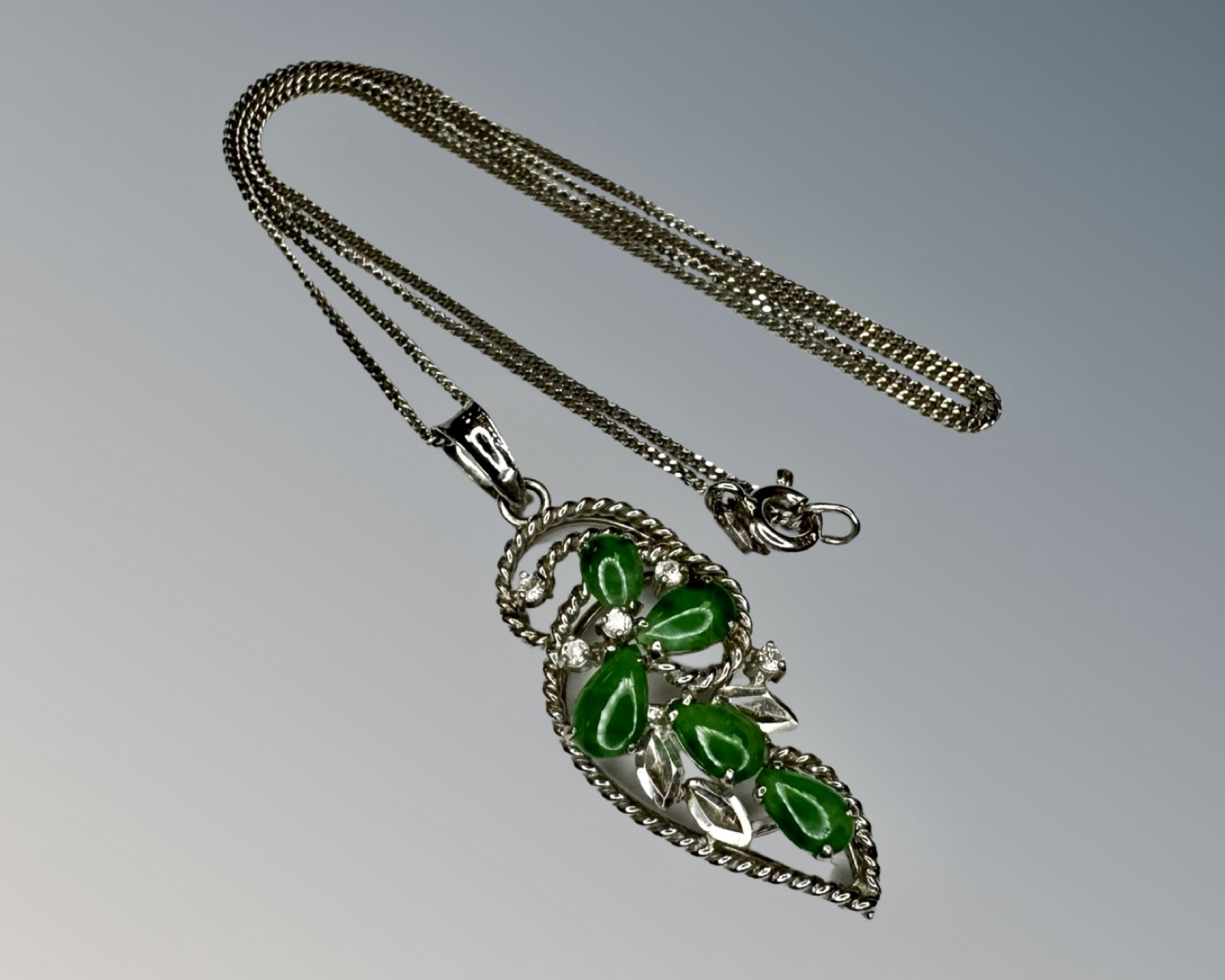 A 9ct white gold jade and diamond pendant on 14ct gold chain.