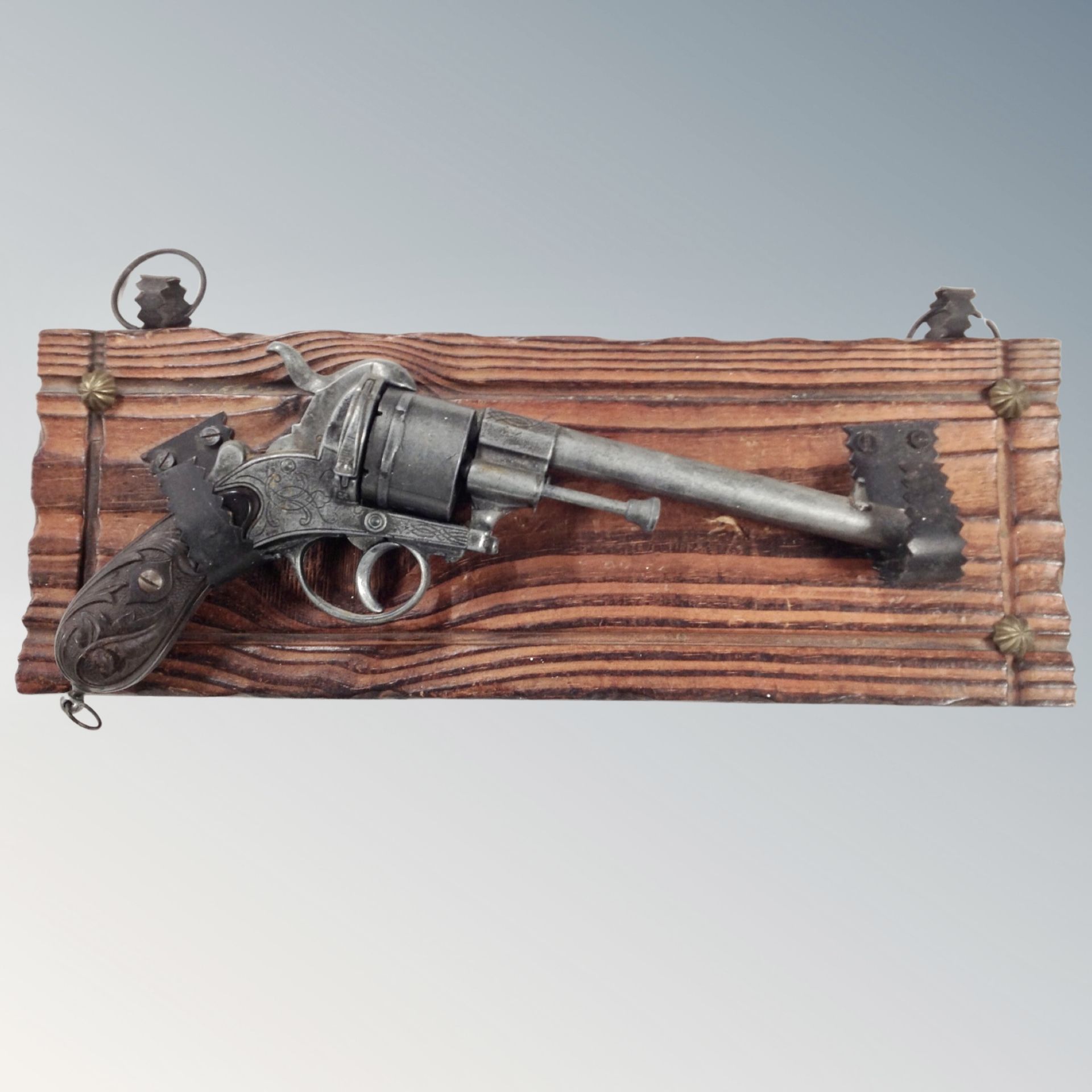 A decorative reproduction revolver mounted on a wooden plaque