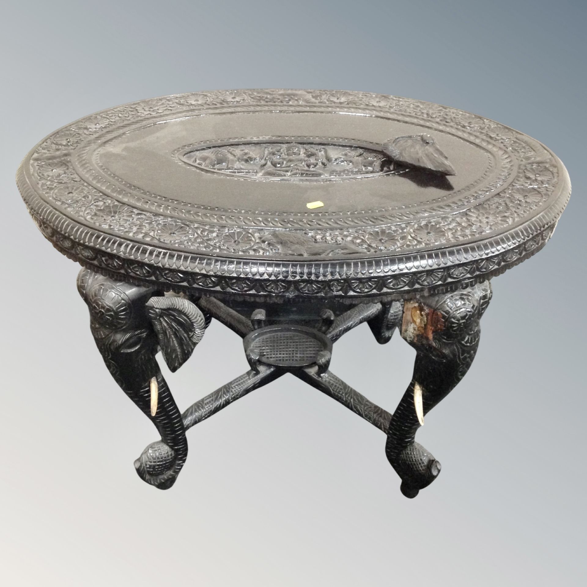 An ebonised Indian carved oval occasional table on elephant legs