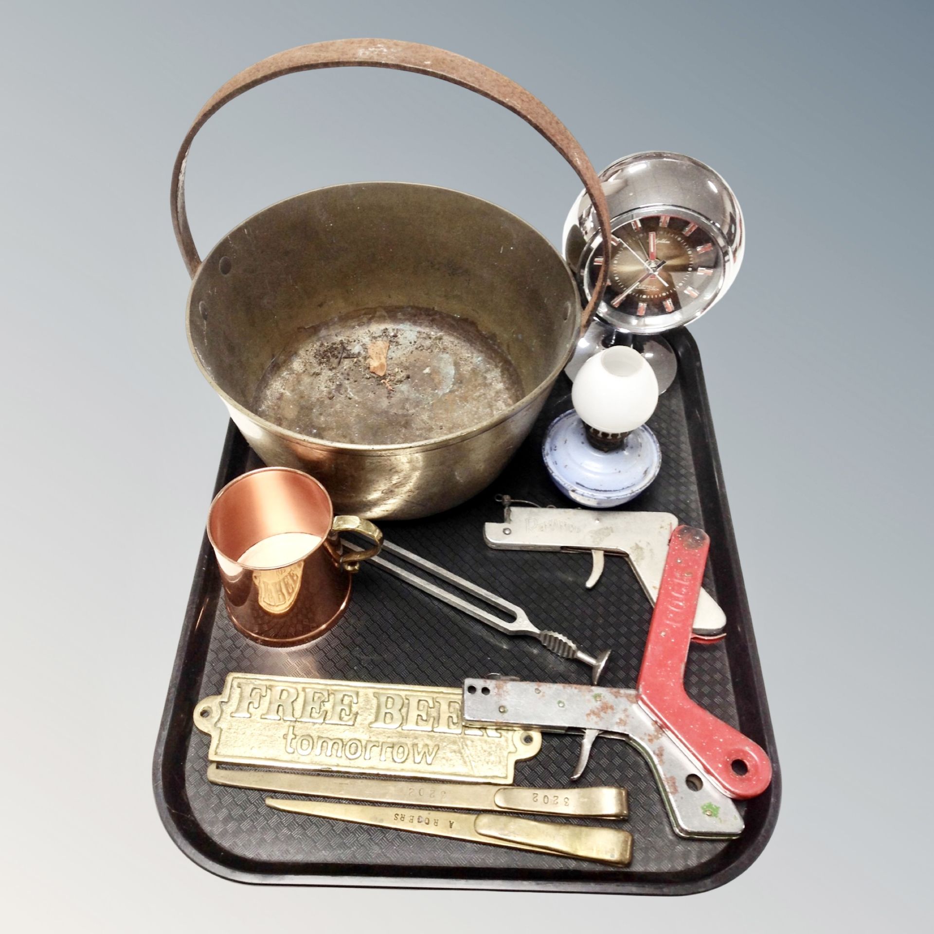 A tray of vintage brass cast iron jam pan, Japanese alarm clock,