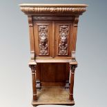 An early 20th century carved oak double door cabinet fitted a drawer on raised pillar legs