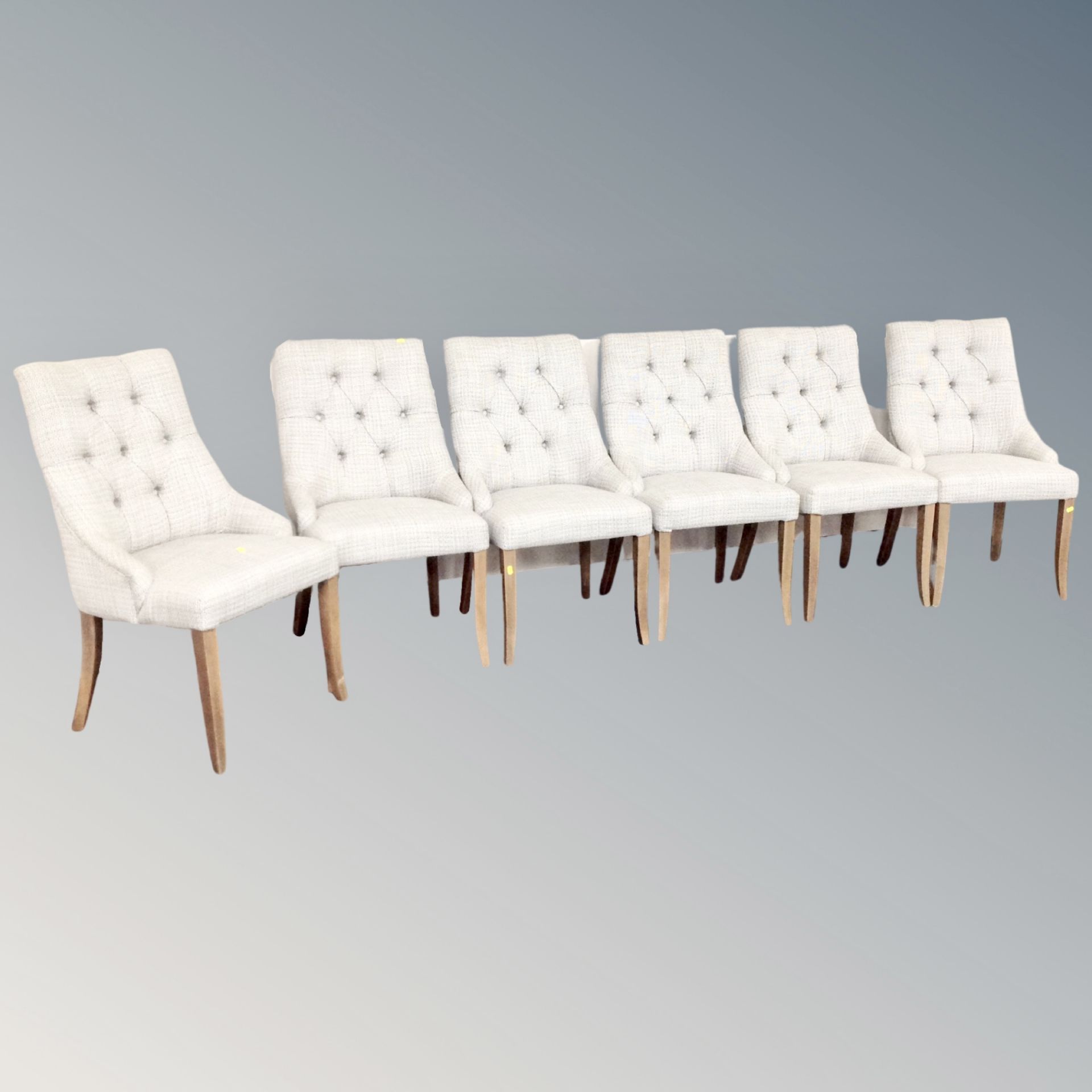 A set of six contemporary dining chairs upholstered in beige buttoned fabric