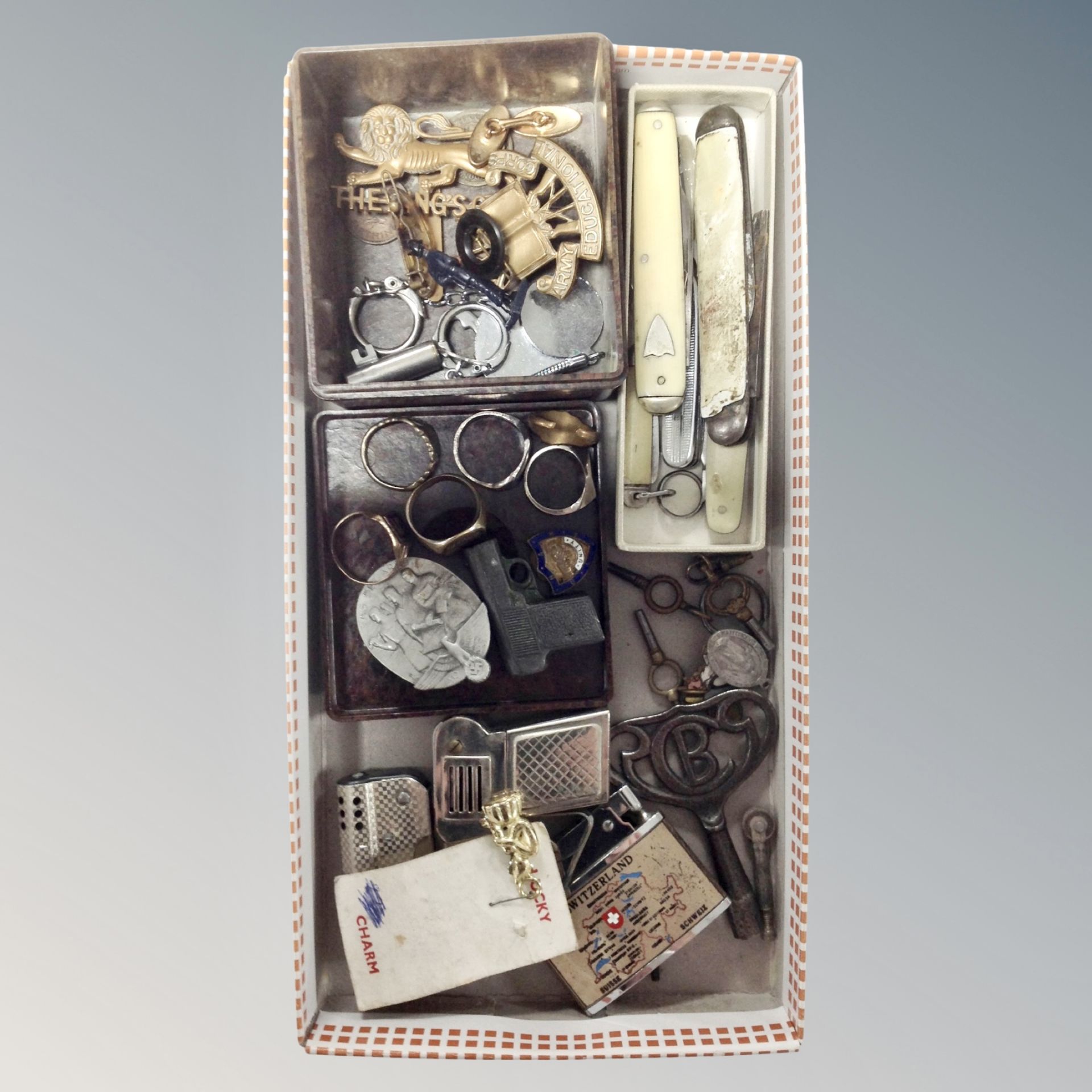 A tray of pocket knives, military badges, pocket lighters in the form of guns,