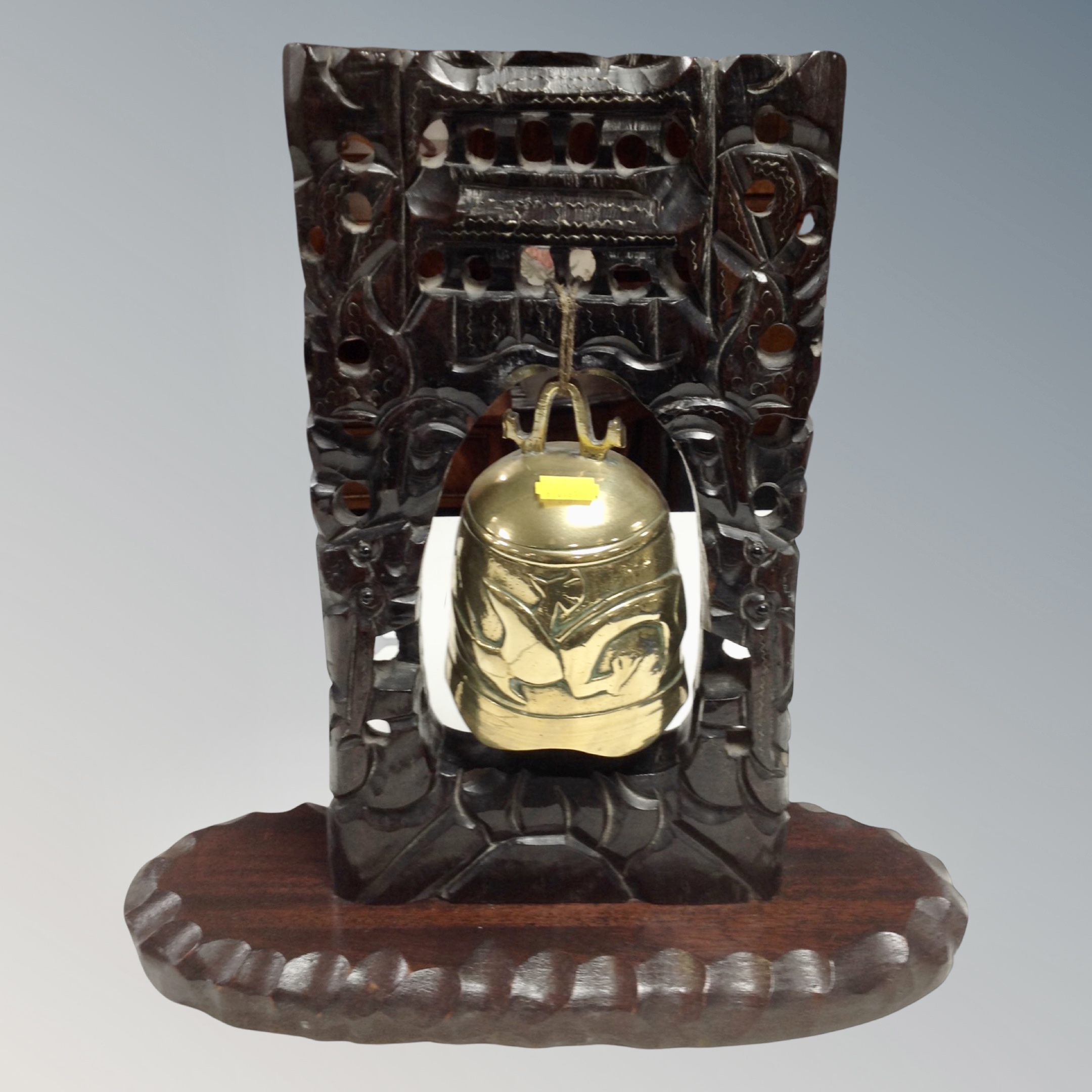 A brass temple bell on carved wooden stand, height 39 cm.