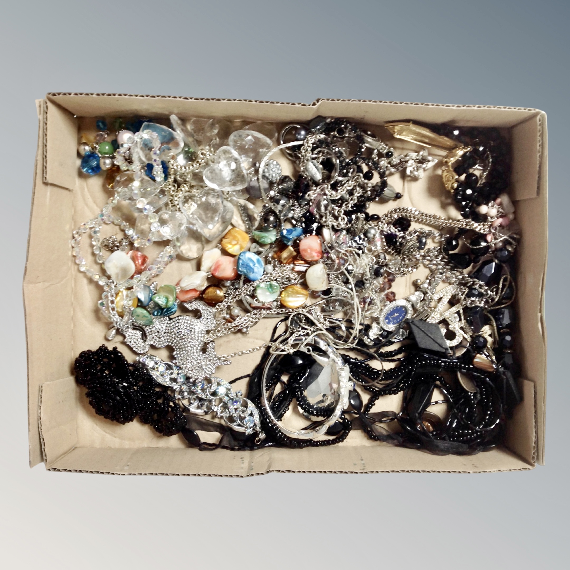 A box containing assorted costume jewellery, oversized horse pendant on chain,