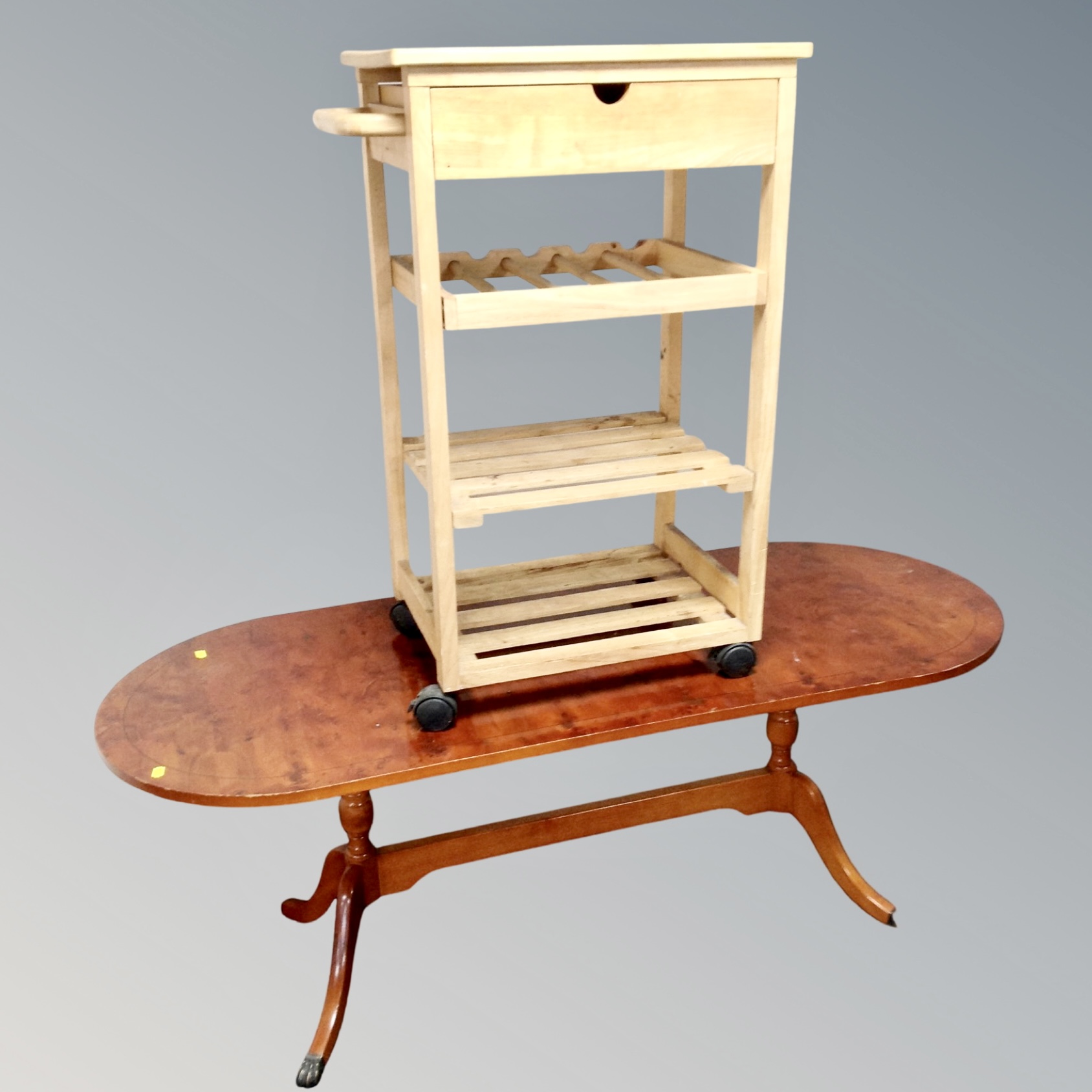 An oval inlaid yewwood twin pedestal coffee table together with a pine kitchen trolley