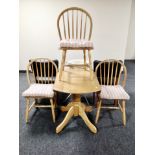 A wooden drop leaf pedestal kitchen table and three chairs