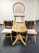 A wooden drop leaf pedestal kitchen table and three chairs