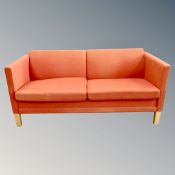 A 20th century Danish two seater settee in rust fabric