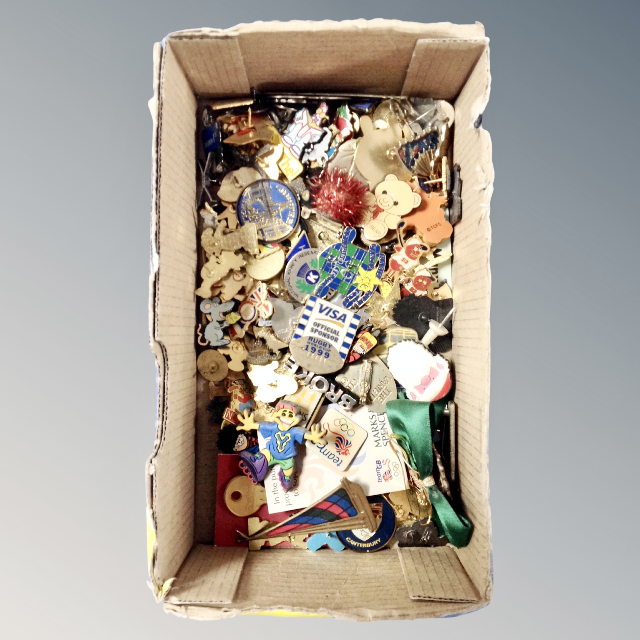 A box of assorted metal and enamelled pin badges