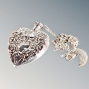 An antique silver perfume heart shaped bottle on white metal chain with charms