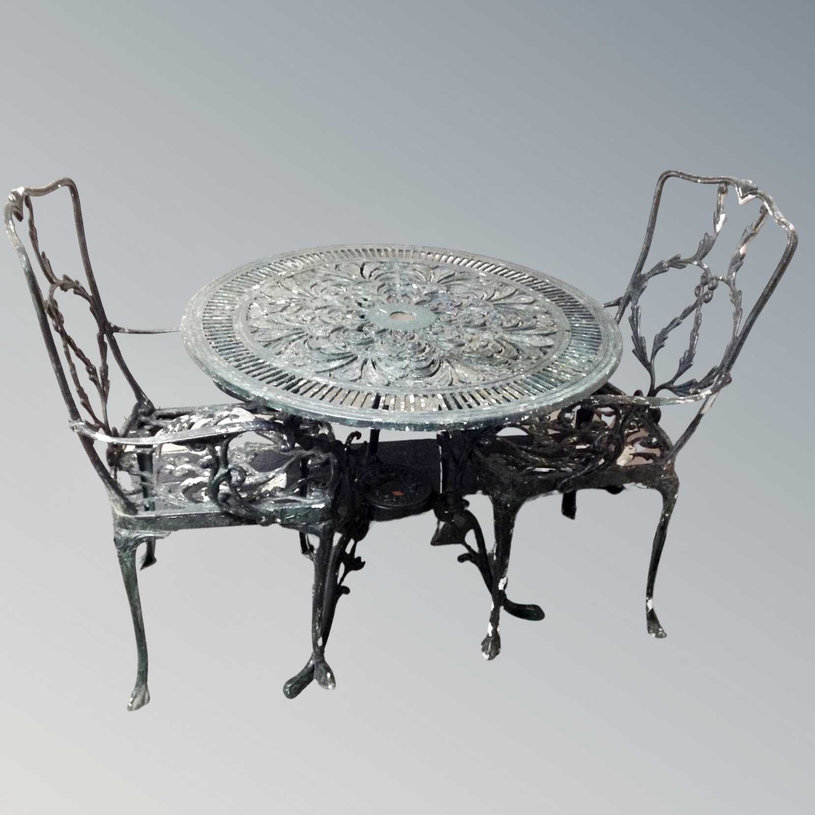 A painted metal circular garden table with two chairs