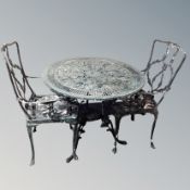 A painted metal circular garden table with two chairs