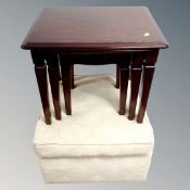 A nest of stag tables together with an upholstered footstool