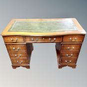 A Georgian style serpentine fronted writing desk fitted with nine drawers and green leather panel