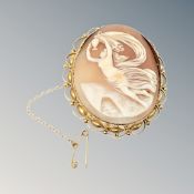 An ornate gold cameo brooch with gold safety chain