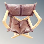 A 20th century folding X-framed armchair with brown leather cushion (af)