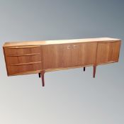 An A H Macintosh teak double door long low sideboard fitted with three drawers