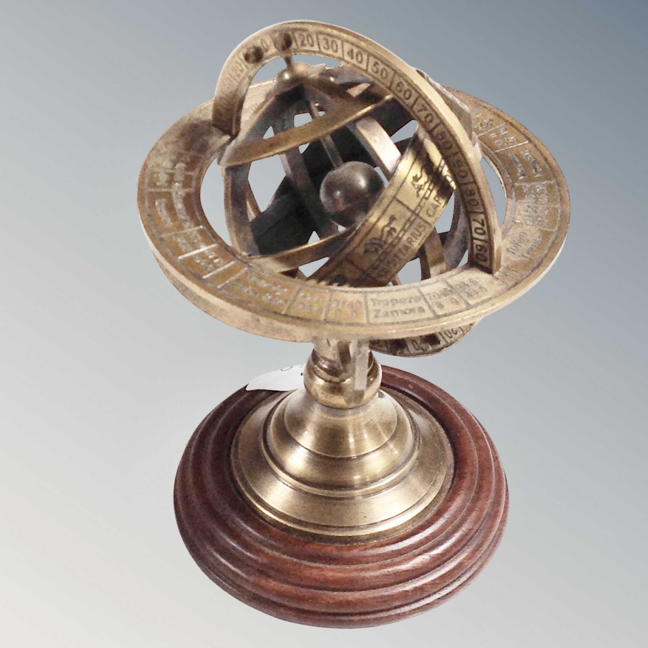 A miniature brass armilary sphere on wooden stand,