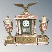 A French 19th century rouge marble and brass clock garniture surmounted by an eagle,