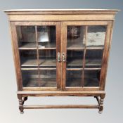 An Edwardian oak double door glazed bookcase on raised legs