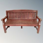 A wooden slatted garden bench together with pair of similar armchairs