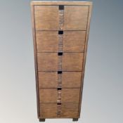 A narrow six drawer chest in an antique finish, 128cm high by 48cm deep by 42cm high.