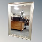 A bevelled mirror in a silvered step frame