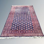 A Bokhara design rug on blue ground, 190 cm x 270 cm CONDITION REPORT: Moth damaged.