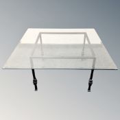 A contemporary square glass topped coffee table on metal base