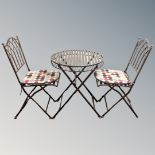 A wrought metal folding patio table together with two chairs