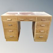 A mid century oak twin pedestal writing desk with nine drawers