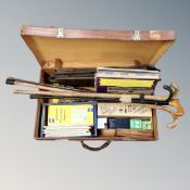 A vintage leather luggage case containing vinyl records, light bulbs, folded maps, bundel of sticks,